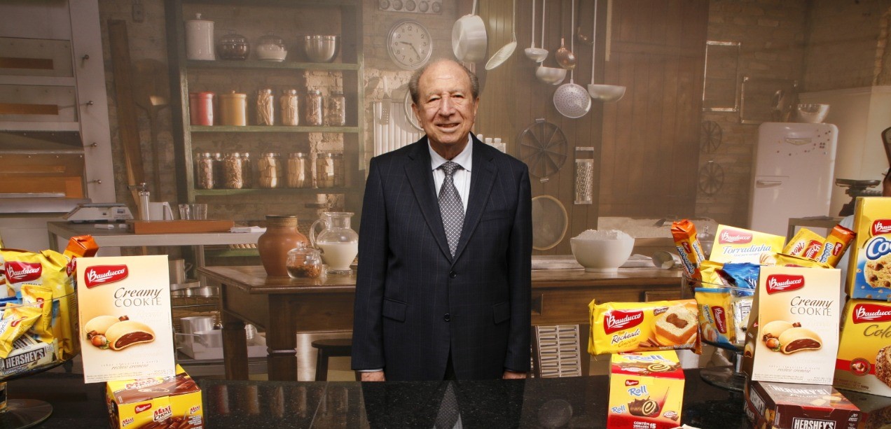 Executivo ao lado de produtos da linha atual da Bauducco, como o Creamy Cookie e os wafers. Fonte: Imagens divulgação.